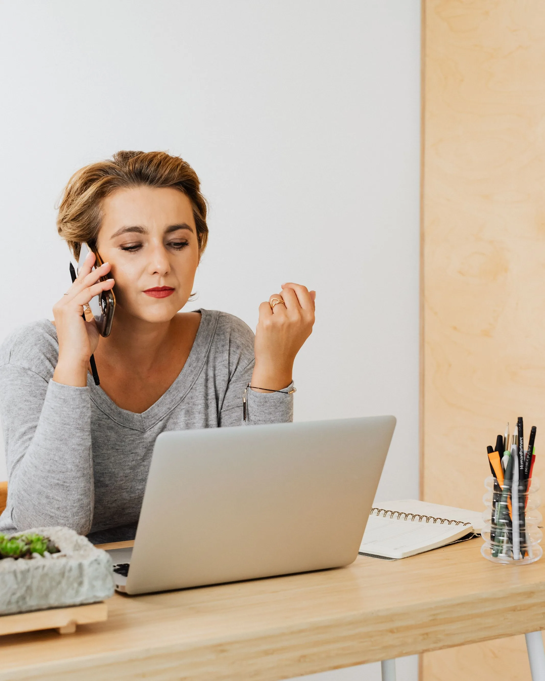 Dirigeante à son bureau, téléphone en main, ordinateur portable et carnet ouverts devant elle